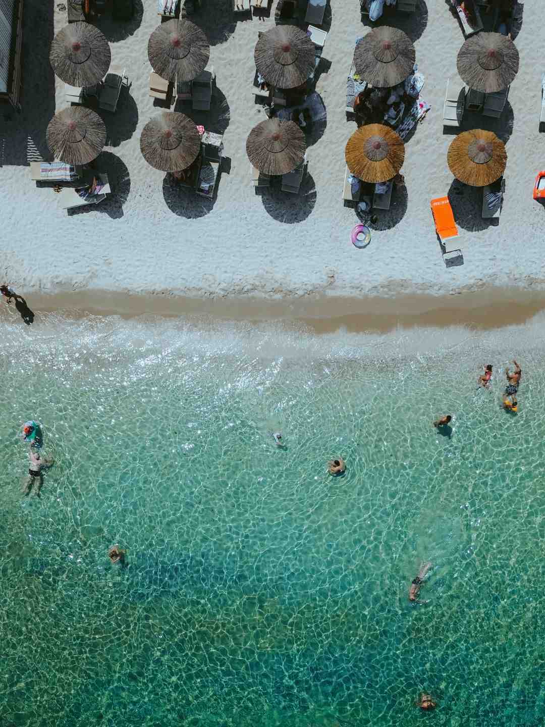 Vista dall'alto della spiaggia di Ezzi Mannu con ombrelloni di paglia sulla sabbia chiara e bagnanti nell'acqua cristallina