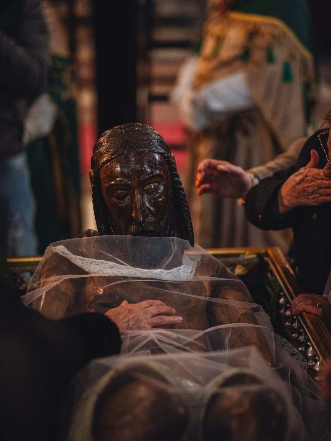 Donne toccano il Cristo sceso dalla Croce durante la Settimana Santa a Sassari